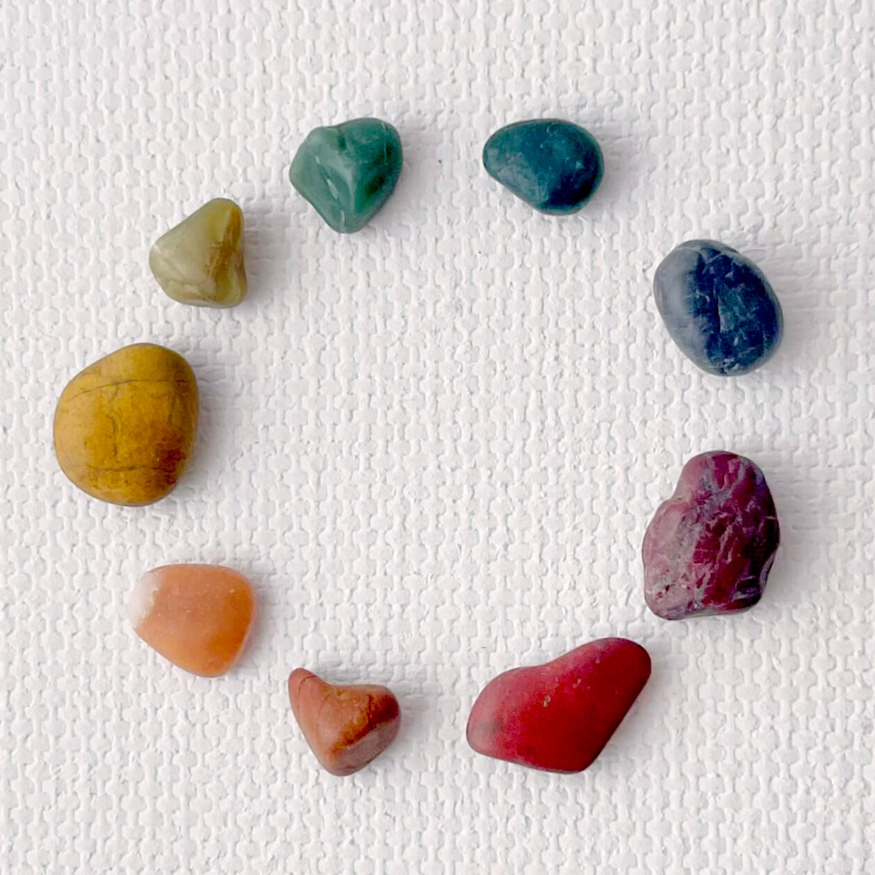 A rainbow array of pebbles arranged in a circle.